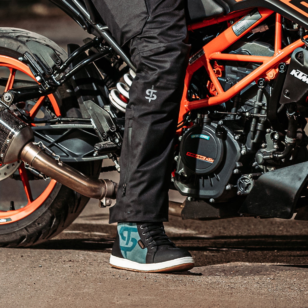 biker wearing waterproof trousers paired with black and blue waterproof trainers for men and women