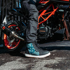 side view of biker on motorbike wearing black and blue suede waterproof hi tops