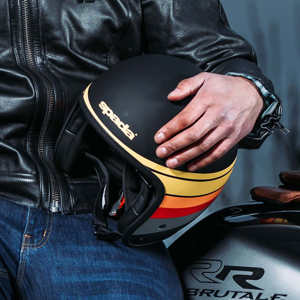 biker wearing black leather biker jacket and holding a black open face motorbike helmet